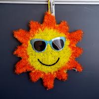 Sun wearing sunglasses hanging from chalkboard